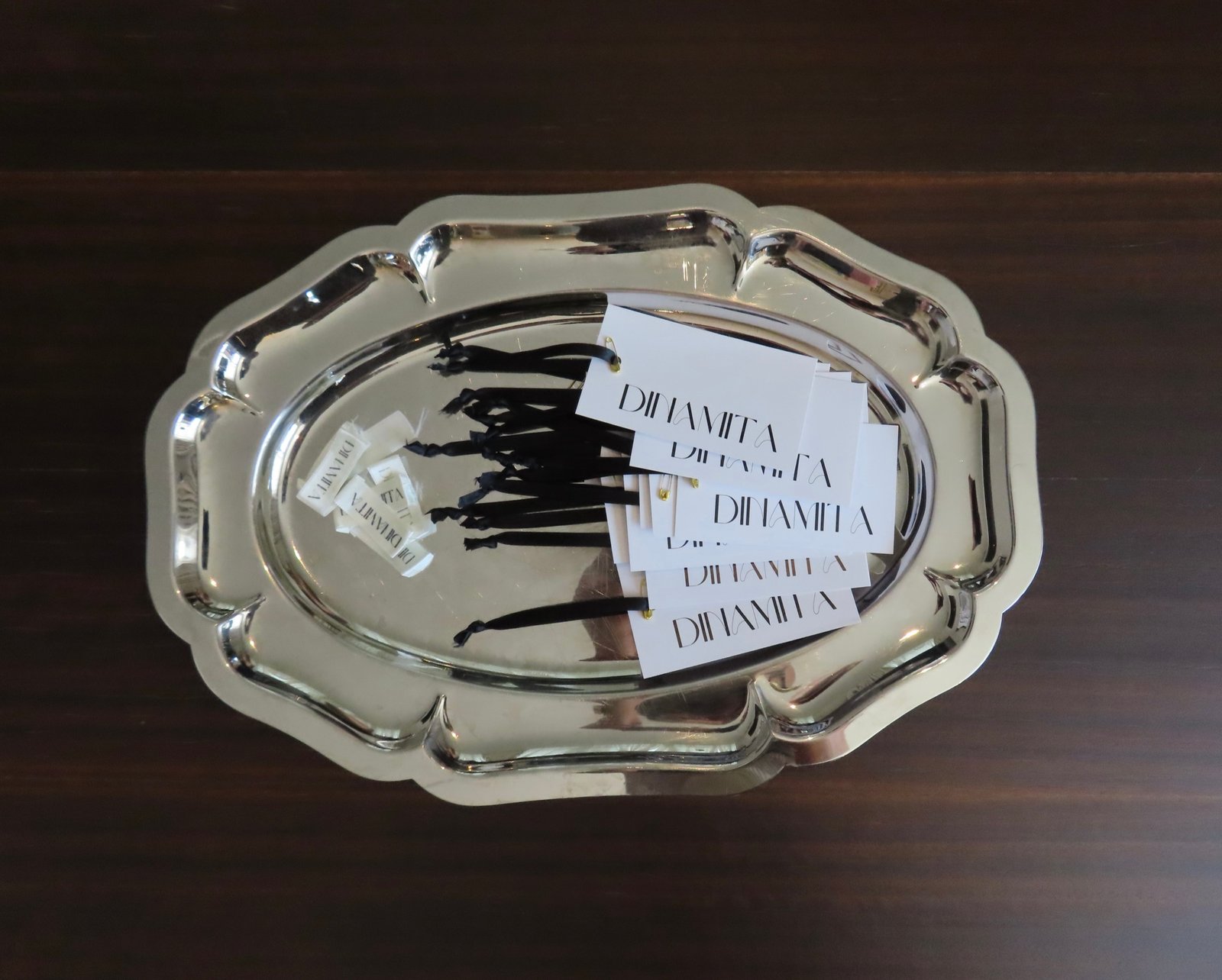 Tarjetas y lazos DINAMITA sobre bandeja, detalle de marca